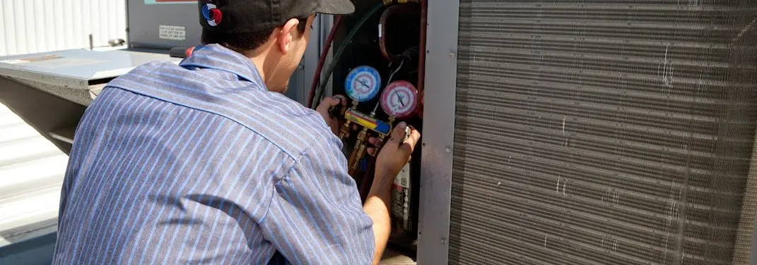HVAC technician servicing a condenser unit in Friendly